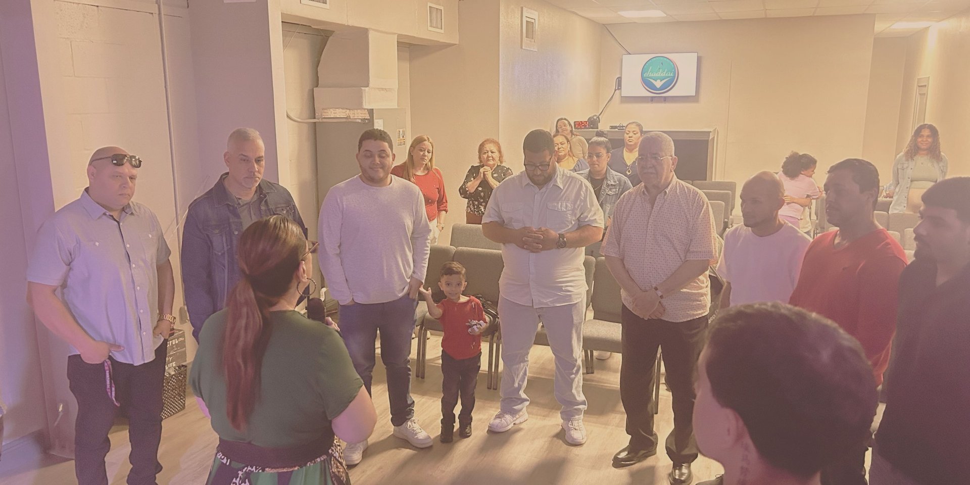 Group of diverse people standing in a circle during an indoor meeting or gathering in a well-lit room